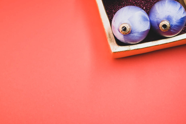 A top view of Christmas ornaments in a luxurious bowl filled with small red rocks on pink background - Valokuva, kuva