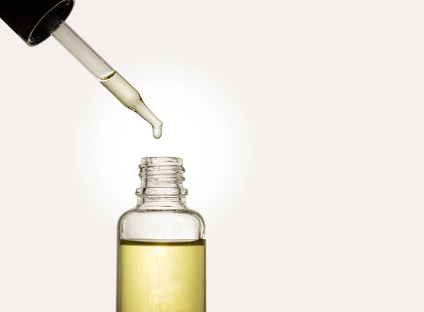 Pipette with cosmetic oil on a light background. A bottle of cosmetics. Skin, hair, and body care. Spa. - Photo, Image