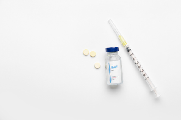 Bottle of insulin with syringe and pills on white background. Diabetes concept - Photo, Image