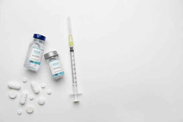 Frascos de insulina con jeringa y pastillas sobre fondo blanco. Concepto de diabetes - Foto, Imagen