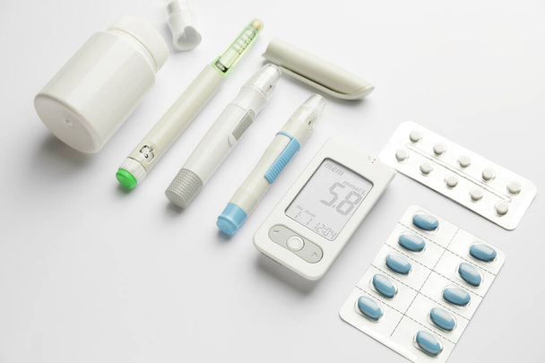Glucomètre, pilules, stylos lancettes et seringue sur fond blanc. Concept de diabète - Photo, image