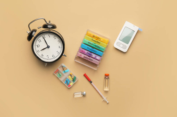 Glucometer with medications, syringe and alarm clock on color background. Diabetes concept - Photo, Image