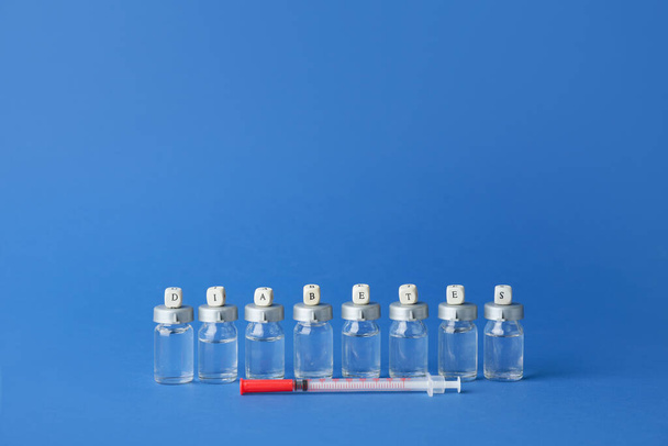 Flaconi di insulina con siringa e scritta DIABETES sullo sfondo a colori - Foto, immagini