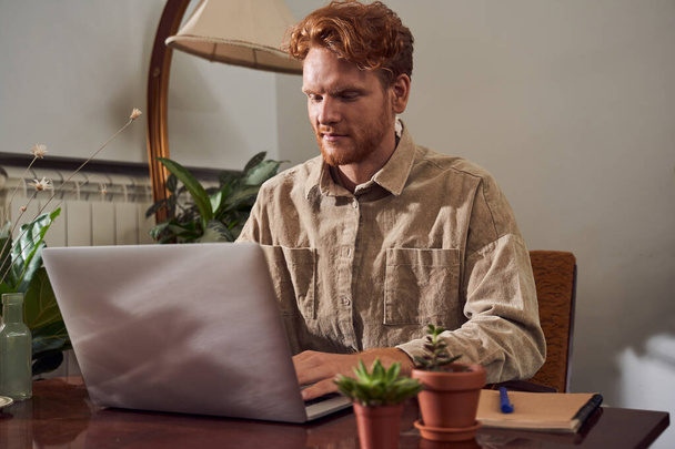 Red head worker with laptop sitting at table - Foto, afbeelding