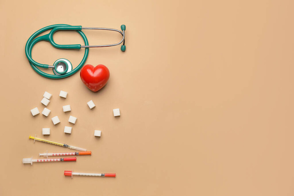 Stethoscope with heart, sugar cubes and syringes on color background. Diabetes concept - Valokuva, kuva