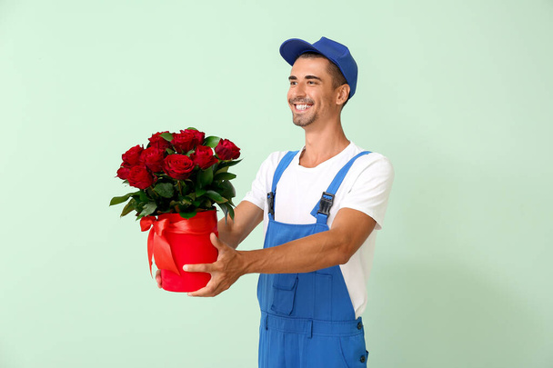 Delivery man with bouquet of flowers on color background - Fotografie, Obrázek