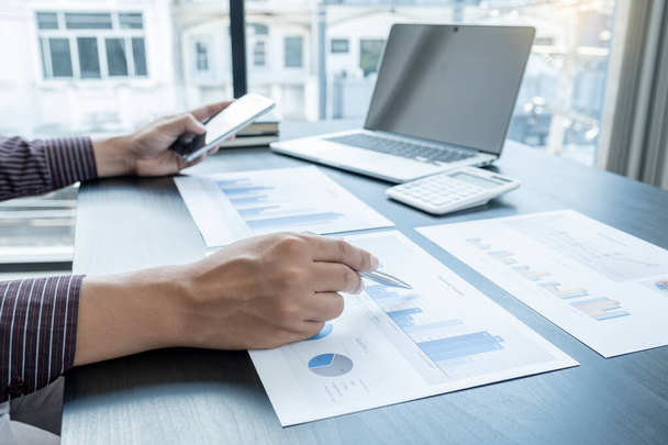 The hands of a male businessman are analyzing and calculating the annual income and expenses in a financial graph that shows results To summarize balances overall in office. - Photo, Image