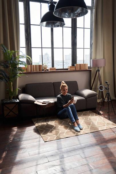 Vrolijke blogger ontspannen thuis in comfortabele woonkamer - Foto, afbeelding