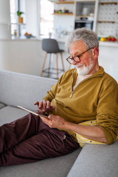 Tecnologia, vecchiaia, persone e stile di vita. Uomo anziano con tablet pc relax a casa - Foto, immagini