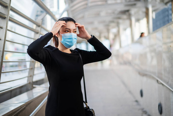 business woman has a headache and wearing medical mask for protection from coronavirus (covid-19) pandemic in the city - Foto, imagen