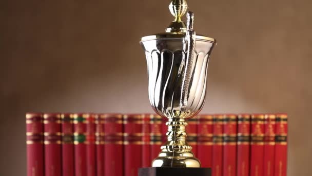 zilveren trofee voor de 1e plaats draaiend en draaiend voor rode boeken op een bruine achtergrond - Video