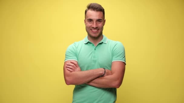 casual guy standing with his arms crossed, smiling, sticking his hands in his pocket, looking away then looking at the camera and laughing on yellow background - Footage, Video