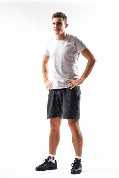 Athletic man on a light background in full growth and jogging charging shorts sneakers t-shirt - Foto, Imagem
