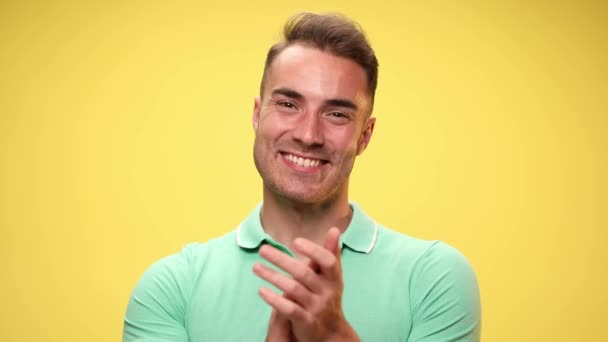 knap jong casual man klappen handen, geven een duim omhoog, wijzen naar de camera, glimlachen en goedkeuren met zijn hoofd op gele achtergrond - Video
