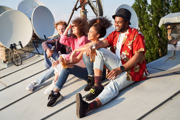 Happy young people drinking beer on urban roof - Foto, Bild