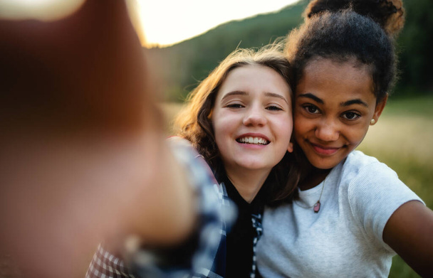 Edessä näkymä nuorten teini tyttöjen ystäviä ulkona luonnossa, ottaen selfie. - Valokuva, kuva