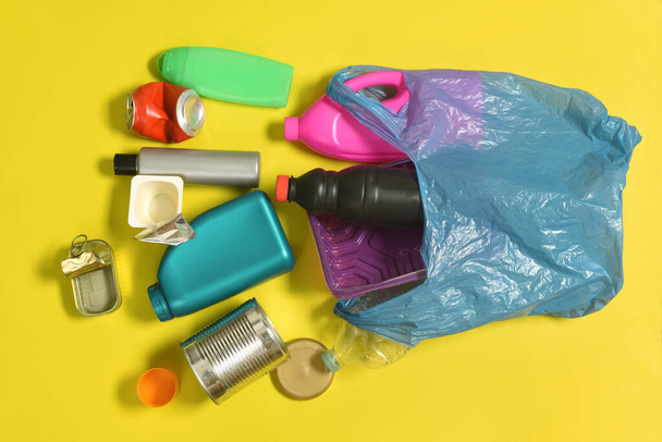 saco de lixo aberto com garrafas de plástico e pode se espalhar no fundo amarelo - Foto, Imagem