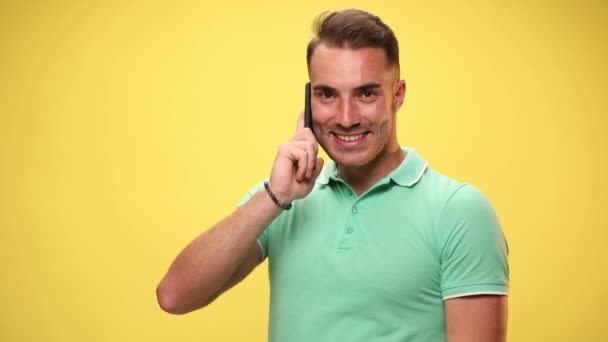 casual man talking on the phone, being shocked, slapping his face, puffing his cheeks on yellow background - Footage, Video