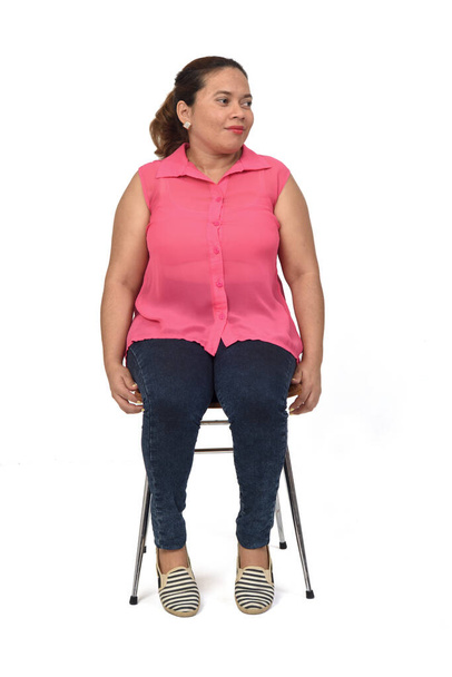 portret van een vrouw zittend op een stoel op een witte achtergrond, kijken kant - Foto, afbeelding