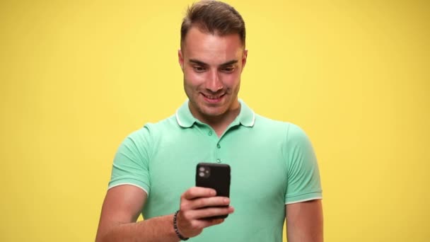 Gelegenheitsmensch, der auf seinem Handy SMS schreibt und dann schockiert ist über das, was er sieht, ihm ins Gesicht schlägt, Wangen auf gelbem Hintergrund bläst - Filmmaterial, Video