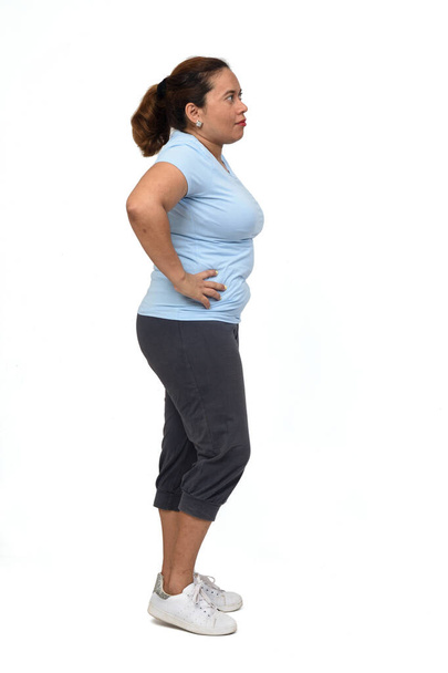  vista lateral de una mujer con ropa deportiva sobre fondo blanco, manos en la cadera - Foto, Imagen