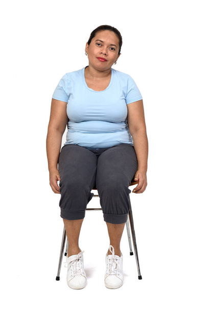 front view  of a woman sitting on a chair looking at camera on white background - Foto, afbeelding