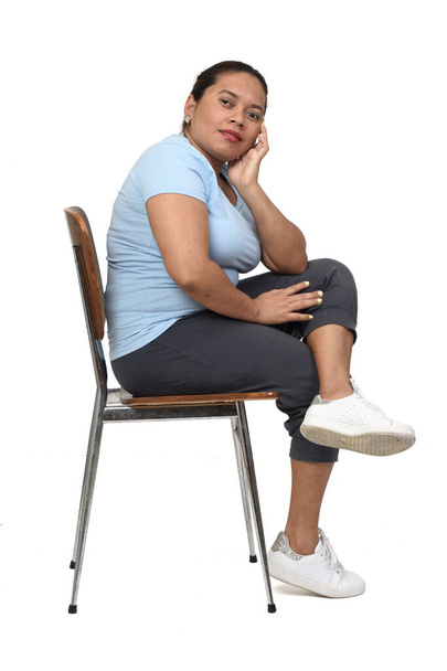 side view of a  woman sitting on a chair looking at camera on white background - Foto, afbeelding