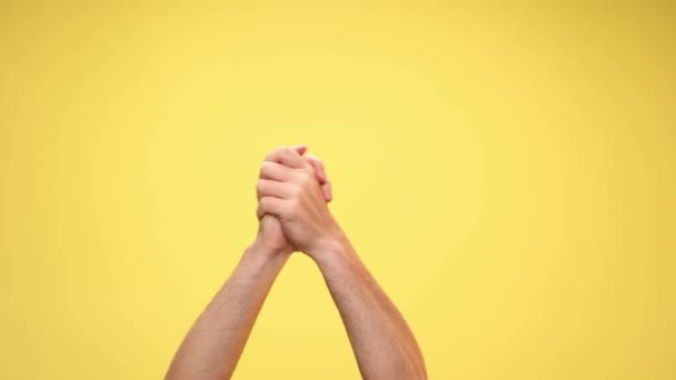 twee armen schudden handen, zwaaien vuisten, geven high five met de camera op gele achtergrond - Video