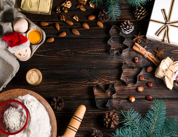Top view των μπισκότων Χριστουγέννων κοντά στα συστατικά, καλούπια ζύμης σε ξύλινο τραπέζι - Φωτογραφία, εικόνα