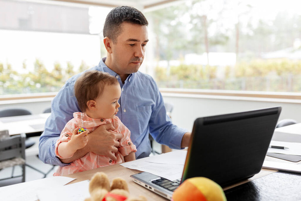 father with baby working on laptop at home office - Photo, image