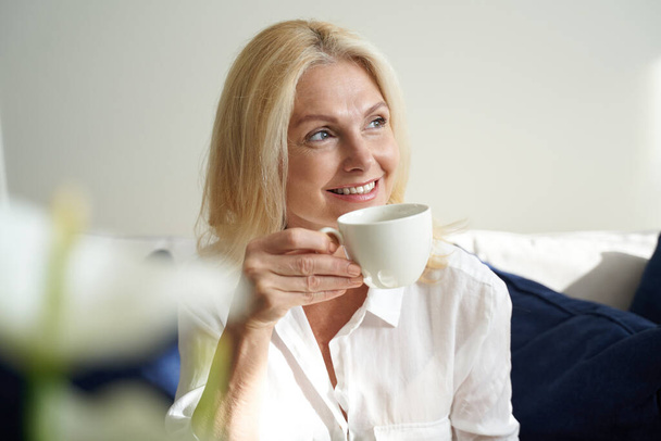Smiling pretty lady is enjoying hot drink - Foto, afbeelding