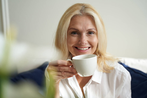 Ευτυχισμένη όμορφη γυναίκα απολαμβάνει ζεστό ποτό - Φωτογραφία, εικόνα