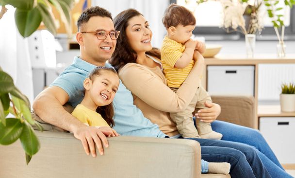 portrait of happy family sitting on sofa at home - Fotoğraf, Görsel