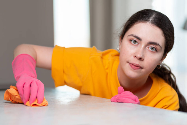 Lavori domestici. Ritratto di casalinga caucasica con guanti di gomma, che pulisce il tavolo con uno straccio. Primo piano. - Foto, immagini