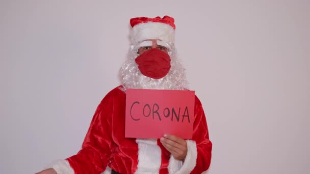 Santa Claus s ochrannou maskou ukazuje znamení se slovy veselá koróna zdarma Vánoce - Záběry, video