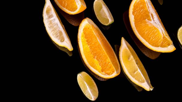 Lime slices orange slices on a black background close up - Photo, image