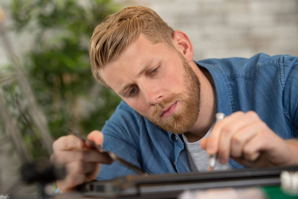 man using screwdriver and repairing a broken laptop for clients - Фото, изображение