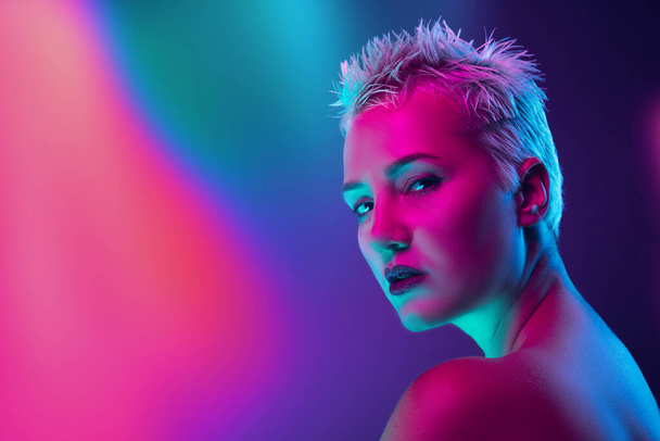 Portrait of female fashion model in neon light on dark studio background. - Fotografie, Obrázek
