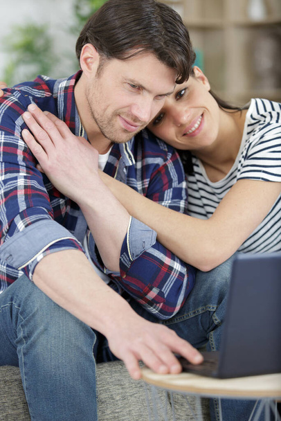 happy man and woman relax on couch hugging watching laptop - Foto, Imagen