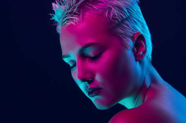 Portrait of female fashion model in neon light on dark studio background. - Valokuva, kuva