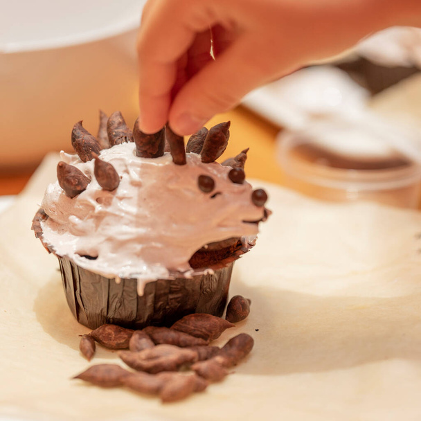 A child decorates a muffin at a cooking class. Kid chef, Focus on the cake - Фото, изображение