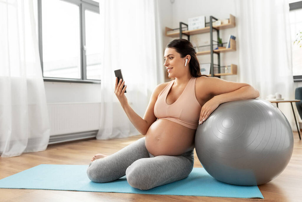 pregnant woman with smartphone and fitball at home - Foto, immagini