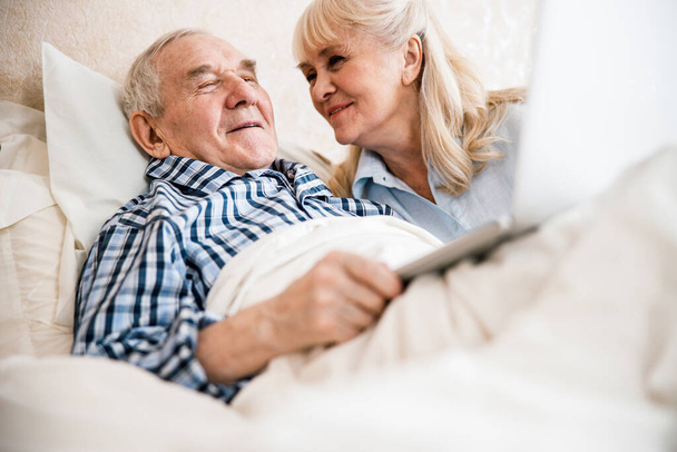 Laughing senior couple lying on bed - 写真・画像