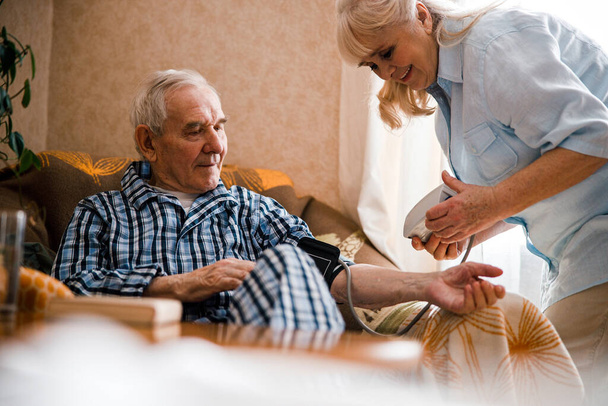 Woman checking husbands blood pressure - Foto, Bild