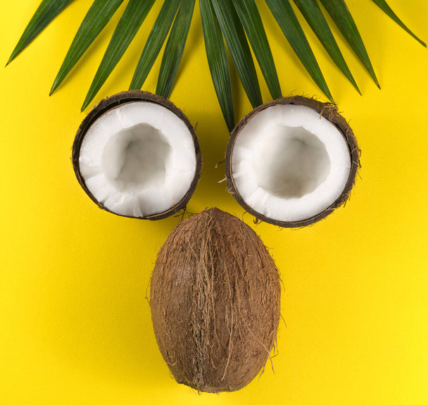 Coconuts and palm leaves on yellow background - Фото, зображення