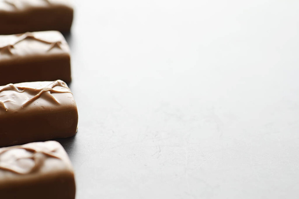 Barre di cioccolato su sfondo nero in retroilluminazione. Cioccolato con ripieno. Dolci dolci per snack e tè. - Foto, immagini