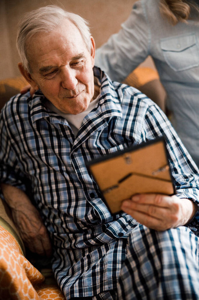 Elderly man looking at the photo in the frame - Foto, Bild