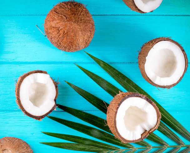 Coconuts with palm leaves on wooden table - Foto, afbeelding