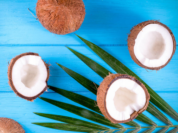 Coconuts with palm leaves on wooden table - Foto, afbeelding