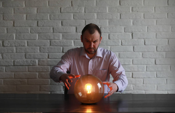 Egy férfi egy jövendőmondó labdával az asztalnál. - Fotó, kép